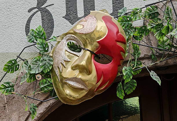 Carnival venetian mask with golden stars confetti on deep red background close up. Luxury masquerade mask. Purim party template.