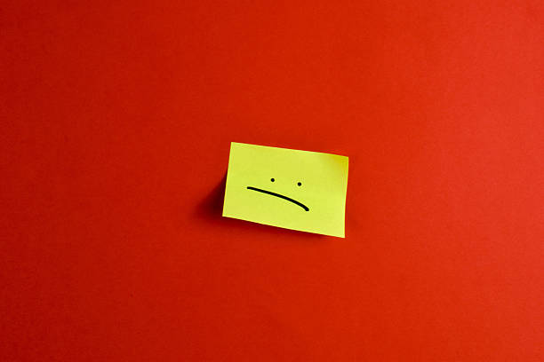 Yellow sticky note with winking smiley face on red background, conveying playful positivity through bold color contrast and minimal design.