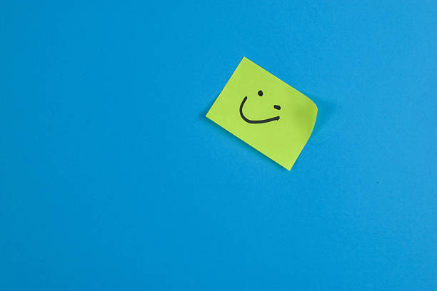 istock Green sticky note with cheerful smiley face on bright blue background, conveying positivity through bold color contrast and minimal design. 2257178139