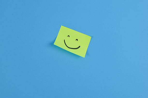 istock Green sticky note with cheerful smiley face on bright blue background, conveying positivity through bold color contrast and minimal design. 2257178165
