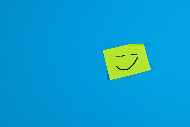 istock Green sticky note with cheerful smiley face on bright blue background, conveying positivity through bold color contrast and minimal design. 2257178178