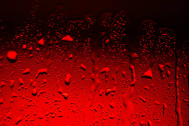 Raindrops on a wet car window with a blurred background. View from inside the vehicle on a gloomy day, creating a moody and atmospheric abstract texture with copy space.