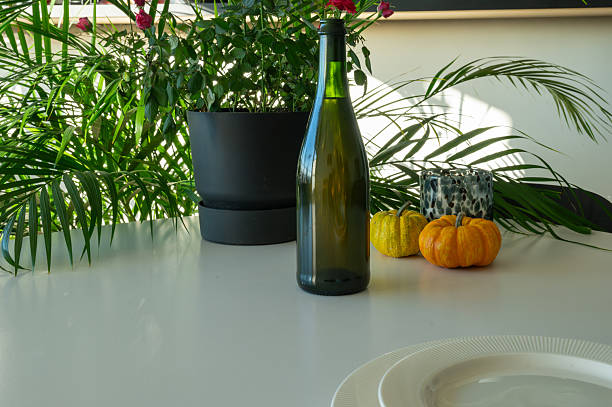 Green glass bottle of wine on the table near two pumkins