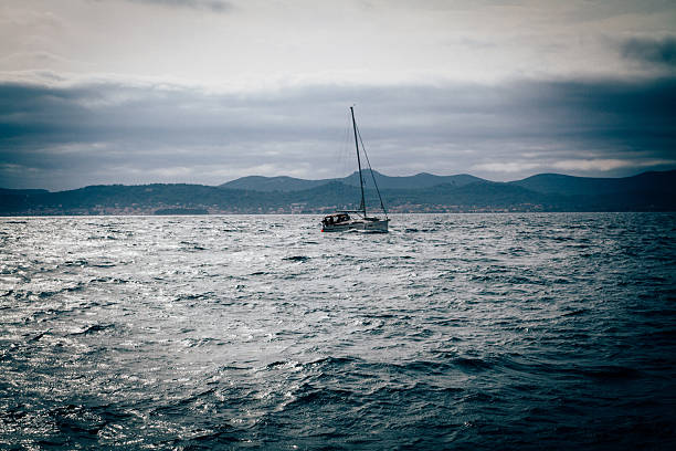 Sailing boat on open water  with coastline in the background