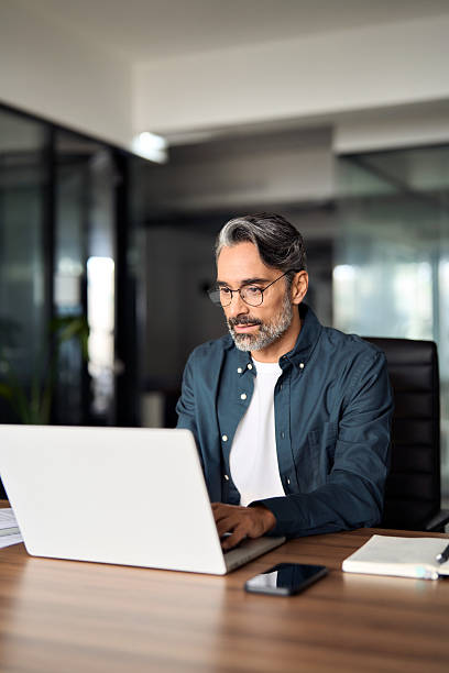 istock Busy middle aged Indian business man using laptop computer in office. Vertical. 2257189711