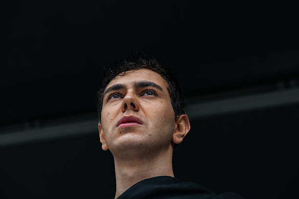 Young man standing outdoors at night with blurry background lights