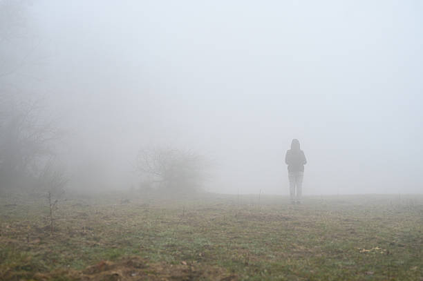 Young man walk on path with wooden stick in misty fog at sunrise, Czech landscape