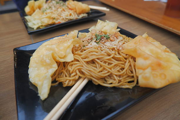 Mie goreng or fried noodles served with chicken and vegetables, on a plate.