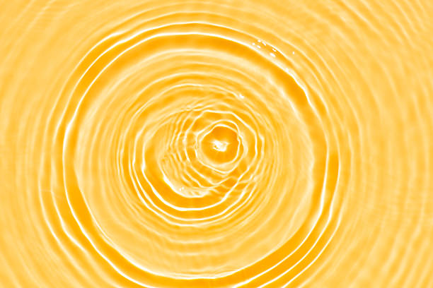 Abstract orange swirl. Orange water bubbles on the surface ripples. Defocus blurred transparent pink colored clear calm water surface texture with splash and bubbles. Water waves with shining pattern.