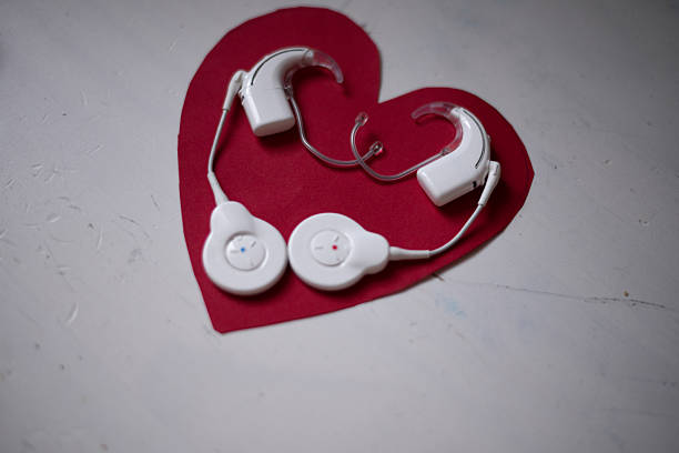 Cochlear hearing implants placed on a heart-shaped background. Concept of hearing care, medical technology, love, inclusion and support for people with hearing loss.