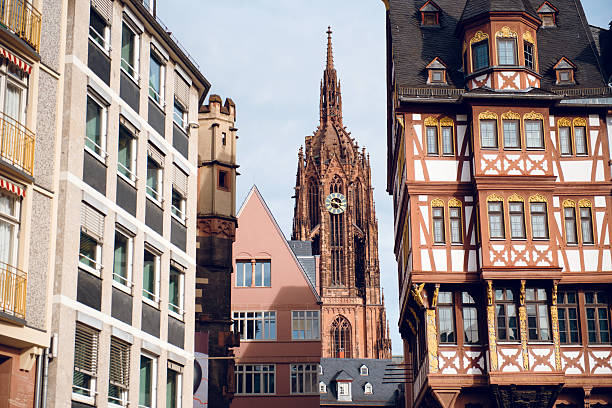 A view of Frankfurt Cathedral's spire rising between historic and modern buildings in the city center