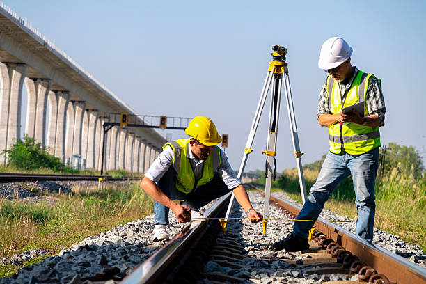 istock Surveyors and civil engineers using a total station and construction blueprints for railway structure infrastructure.