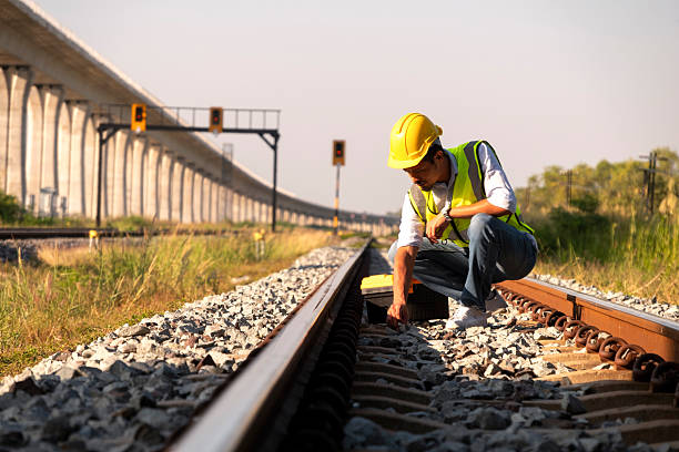 Surveyors and civil engineers using a total station and construction blueprints for railway structure infrastructure.\