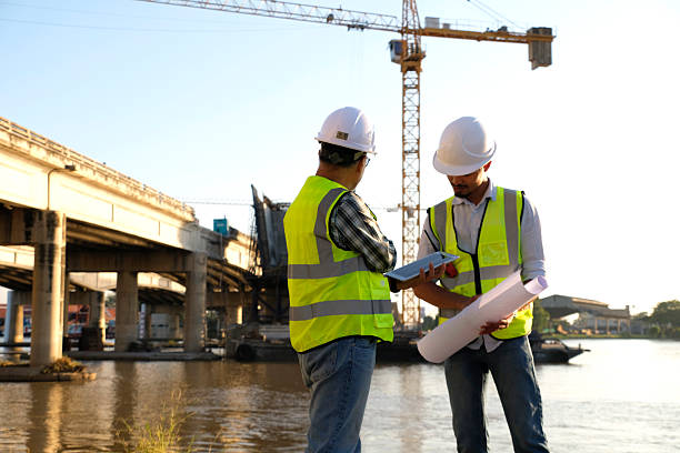 istock Surveyors and civil engineers using a total station and construction blueprints for railway structure infrastructure.