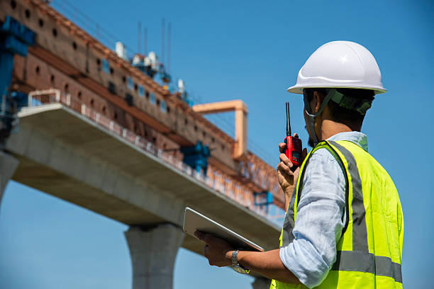 Surveyors and civil engineers using a total station and construction blueprints for railway structure infrastructure.\