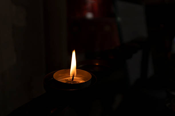 Close up of a single flickering candle flame against a dark, low-key background