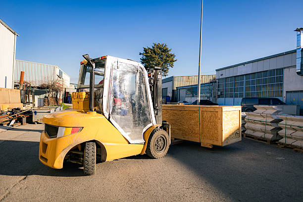 Wide shot of a Caucasian man using a forklift to load a large wooden crate filled with freshly picked rutabaga onto a flatbed truck for transport from his family's farm in rural Oregon.