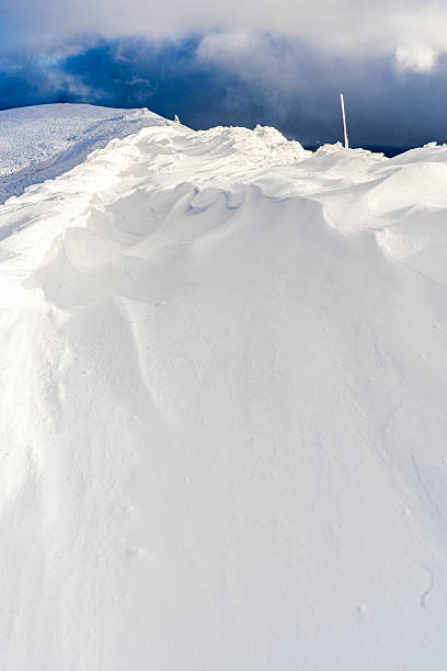A man in a dark jacket shovels snow near a house, a village street, winter, snowdrifts