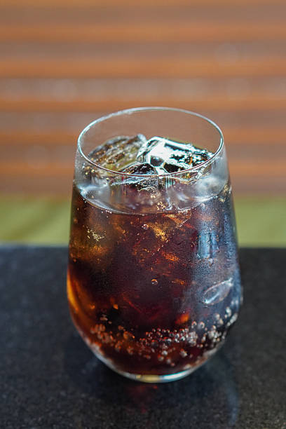 top view cold black drink, ice, in a clear glass, placed on a black marble table, brown wooden wall background, drink, cool, fresh, object, copy space