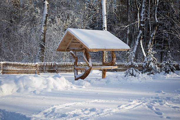 Winter forest scenery with snow, rustic wooden structures and natural textures. Cold season atmosphere, outdoor tranquility, slow living and nature escape.