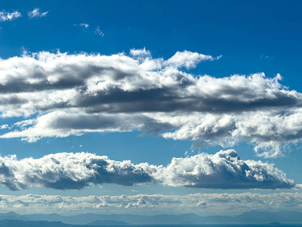 Dramatic cumulus clouds on blue sky over Attica mountains, Greece. Layered white and gray cloud formations above a hazy horizon