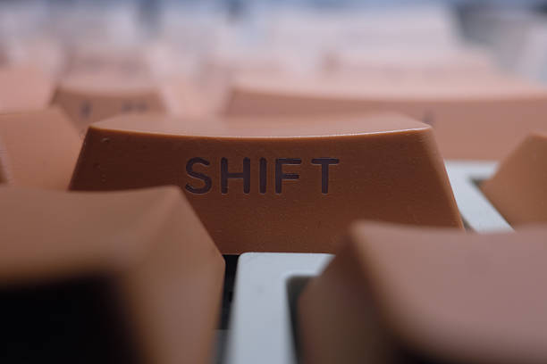 Macro shot of a vintage mechanical keyboard focusing on the Shift key. Warm lighting creates a nostalgic atmosphere, highlighting the textured plastic and retro font of old computing equipment.