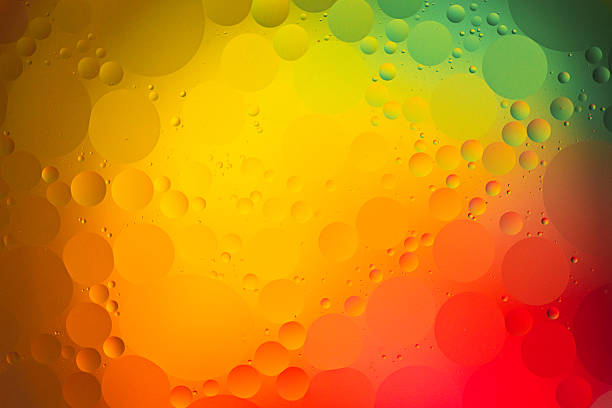 Close up macro image depicting droplets of oil in water on a multi colored background. The oil forms interesting circles and spheres in the water, and colorful background produces an abstract effect.