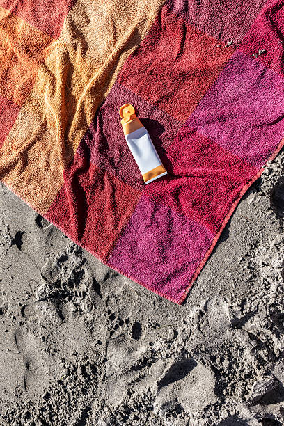 Asturias province. Spain. Sunscreen is lying on a colorful beach towel placed on the sand, suggesting a relaxing day at the beach with skin protection