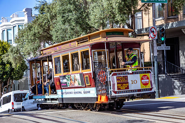 San Francisco, California, USA - 2015, June 24:   cable car, an iconic tourist attraction, descending a steep hill peak overlooking Alcatraz prison island and the bay