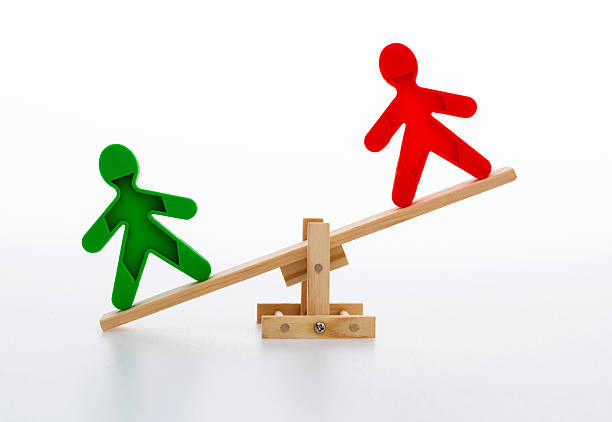 Human figures on wooden seesaw.
