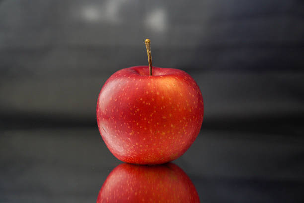 A stunning art photo featuring a ripe red apple set against a beautiful blue gradient background. The vibrant colors and sharp details create an alluring visual contrast that captivates viewers.