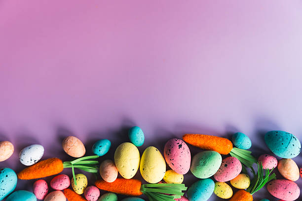 Colorful Easter eggs and carrots on a pink-purple gradient background with copy space. Vibrant, playful layout perfect for holiday designs, seasonal projects, and festive creative content.