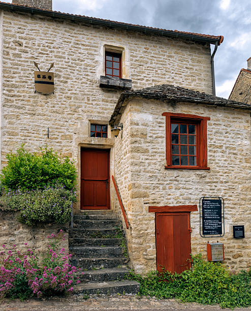 Angular view of a medieval stone house showing the traditional architecture and masonry in the historic center of Chateauneuf-en-Auxois, France. May 2025.
