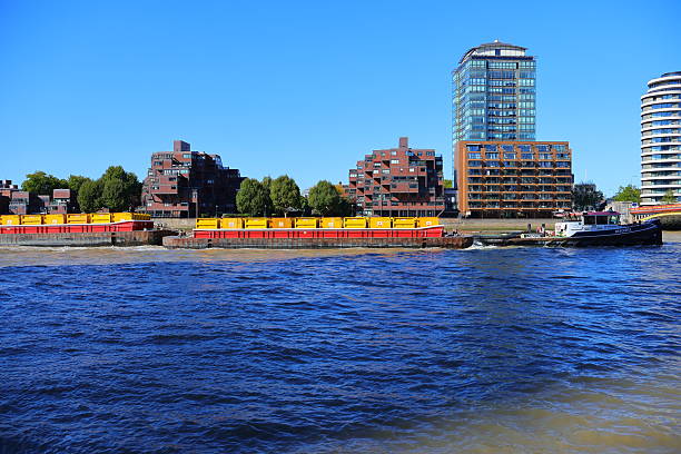 A Thames barge carrying goods or services. Taken near Chelsea Harbour on a flood tide. The River Thames travels through the centre of London. Working barges have been on the Thames for hundreds of years, even supplying other barges with fuel etc.