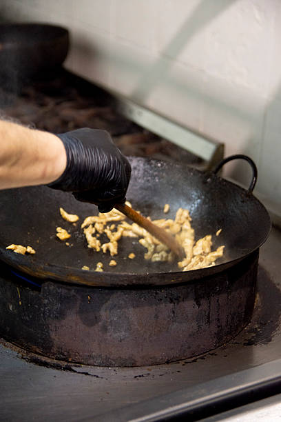 oriental chef stir-frying vegetables in a wok