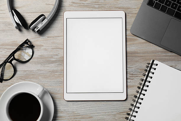 Tablet, notebook, glasses, headphones, coffee and laptop on wooden table, flat lay