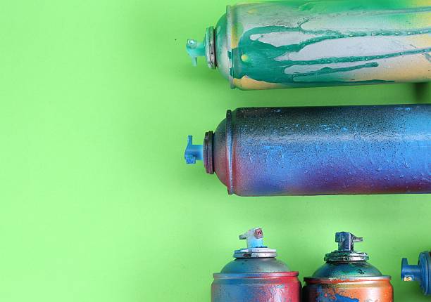 Many spray paint cans on green background, flat lay. Space for text