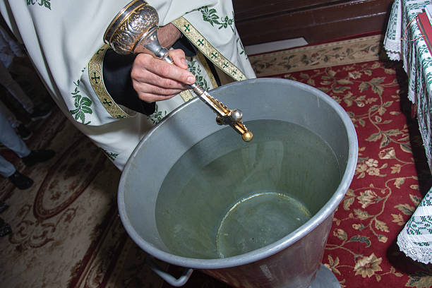 a priest using a vessel to pour water into a large basin during a Christian baptismal ceremony. Baptism is a significant Christian sacrament that symbolizes entry into the Church and new spiritual life.