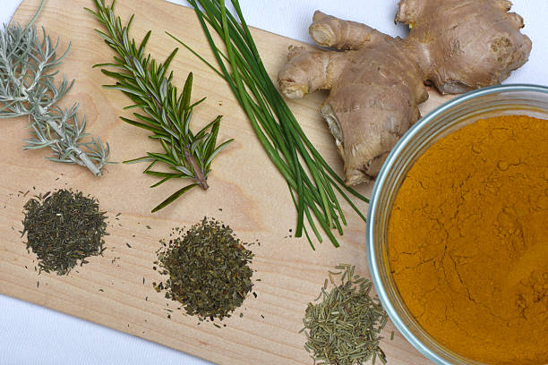 You see a wooden cutting board with several spices and herbs to give a meal taste.
