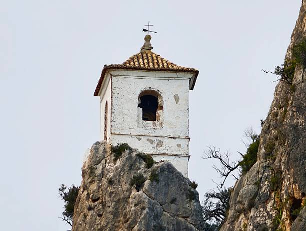 Stone Bell Tower Perched On Rock, Whitewashed Masonry, Cross Finial, Weathered Tiles And Intimate Closeup