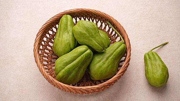 A pile of green chayote squash on bamboo plate