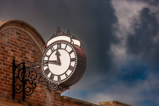 A clear daytime view of Chester's iconic clock tower, featuring its ornate ironwork and prominent clock face. The tower stands tall against a bright sky, surrounded by historic buildings and bustling streets. The well-preserved architecture highlights the timeless charm and rich heritage of the area.