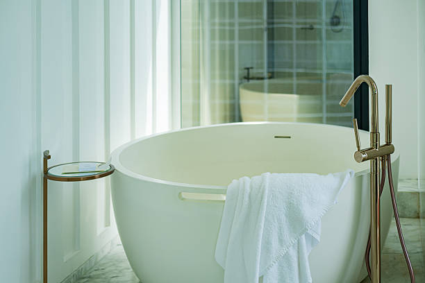 Minimalist white bathroom interior with bathtub, sink, and radiator. Modern home renovation and sanitary ware concept.
