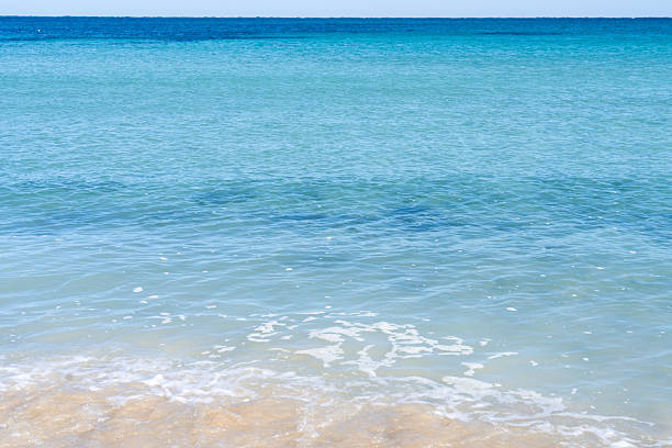 Beach sand background for summer vacation concept. Beach nature and summer seawater with sunlight light sandy beach Sparkling sea water contrast with the blue sky.