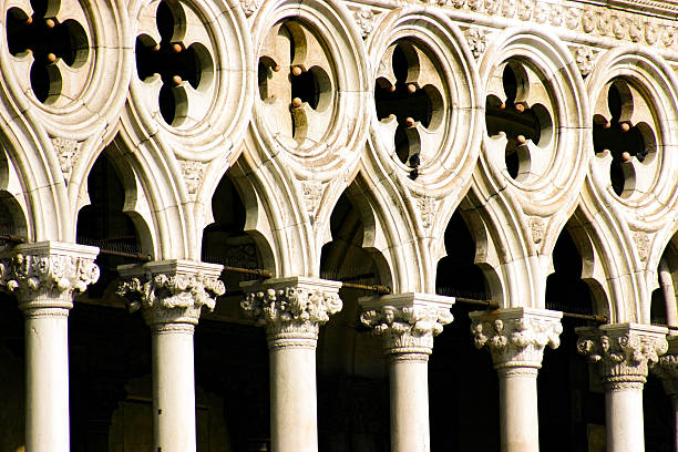 Venice, Italy - December 05, 2025: Historic building features intricate columns and arches, viewed from below with a bright blue sky in the background
