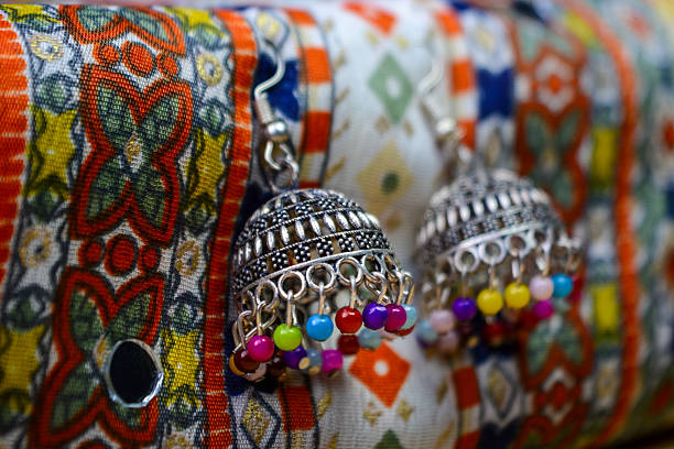 Traditional indian earrings on colorful ethnic fabric background