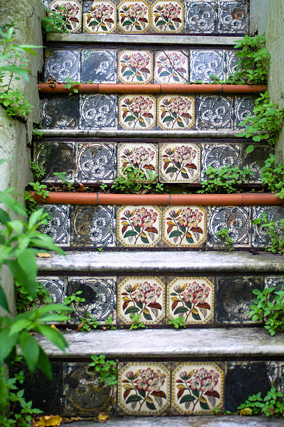 set of decorative tiled steps leads to house with gated entrance. area lush with green plants and features wooden details, creating welcoming and vibrant atmosphere