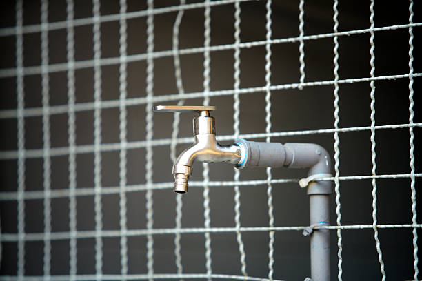 A detailed image of a silver faucet attached to a pipe against a netting background, showcasing the industrial design and functionality in various settings.