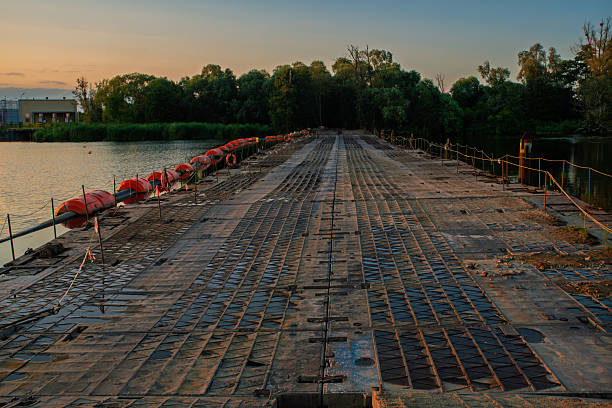 A pontoon bridge made of metal segments spanning a wide river