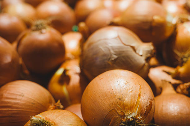 Raw yellow onions filling the frame, creating a natural background for culinary use
